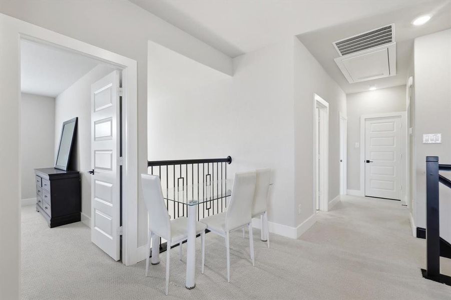Hallway with light carpet, attic access, and an upstairs landing