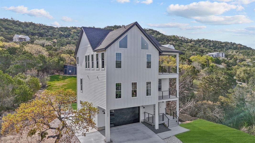 View of front of house featuring a balcony, a garage, driveway, board and batten siding, and a front lawn