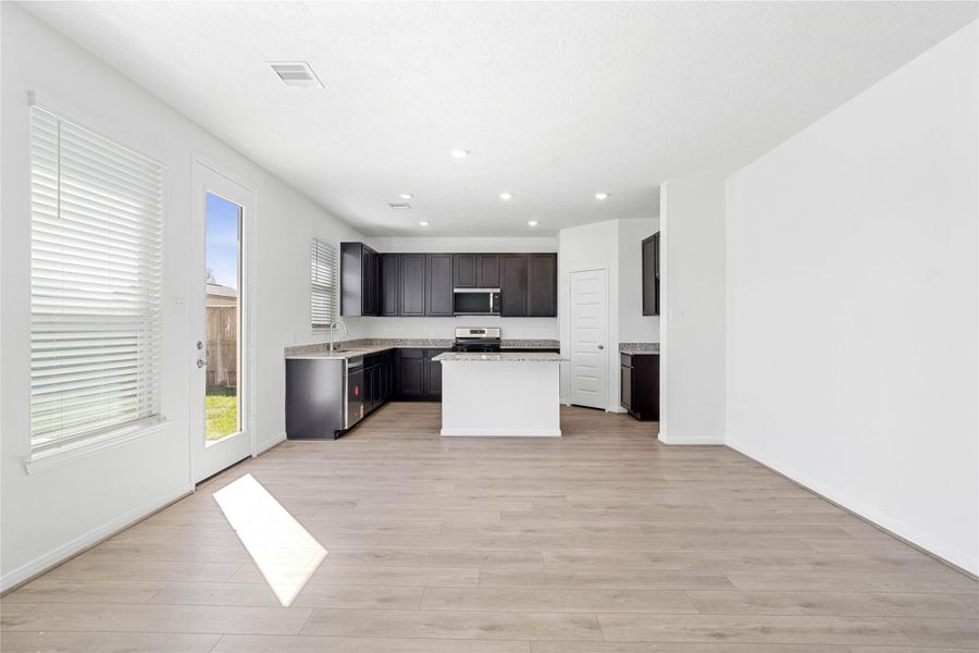 The dining area flows effortlessly from the kitchen, creating the perfect space for everyday meals and entertaining. It features vinyl plank flooring, high ceilings, recessed lighting, large window with blinds, and an access door to the back patio and yard.