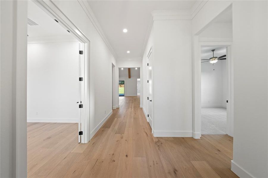 Corridor with light wood-style flooring, crown molding, and recessed lighting