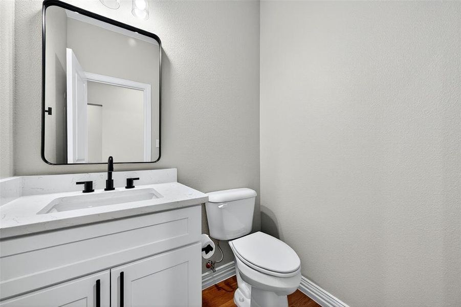 Half bath with vanity, a textured wall, and dark wood-type flooring Half bath with vanity, a textured wall, and dark wood-type flooring