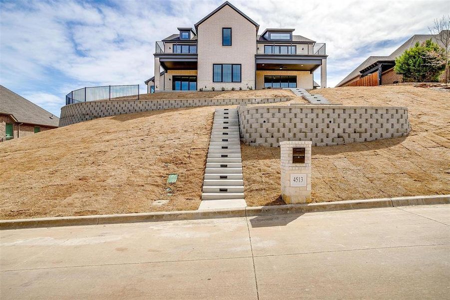 View of front of property with stairs and a balcony