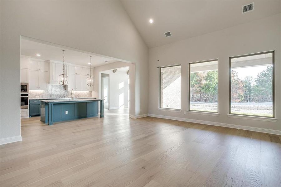 Unfurnished living room featuring high vaulted ceiling, light hardwood / wood-style flooring, and sink