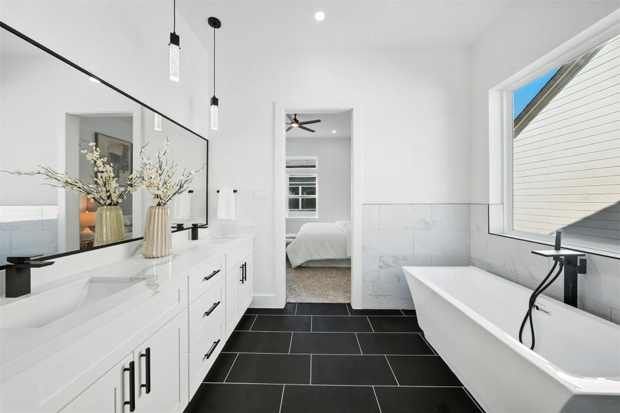 Elegant primary bath with dual vanities, Quartz countertops, and designer lighting. Freestanding soaking tub and spacious glass-enclosed shower create a spa-like feel, complemented by sleek black fixtures and clean, modern finishes. Elegant primary bath with dual vanities, Quartz countertops, and designer lighting. Freestanding soaking tub and spacious glass-enclosed shower create a spa-like feel, complemented by sleek black fixtures and clean, modern finishes.
