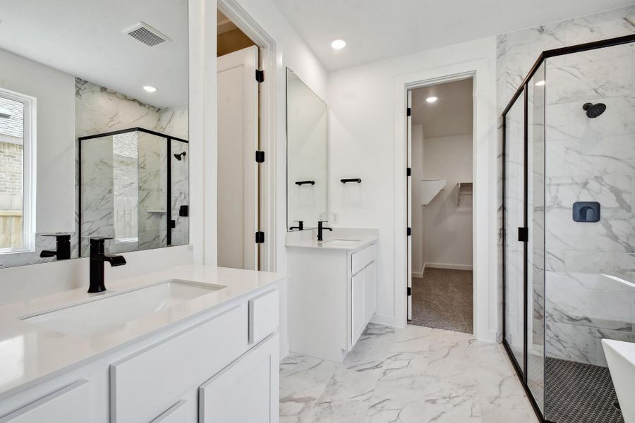 Bathroom with marble tiled flooring, a marble finish shower, two vanities, recessed lighting, and a freestanding tub