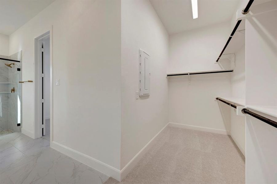Walk in closet featuring electric panel and light marble finish flooring Walk in closet featuring electric panel and light marble finish flooring