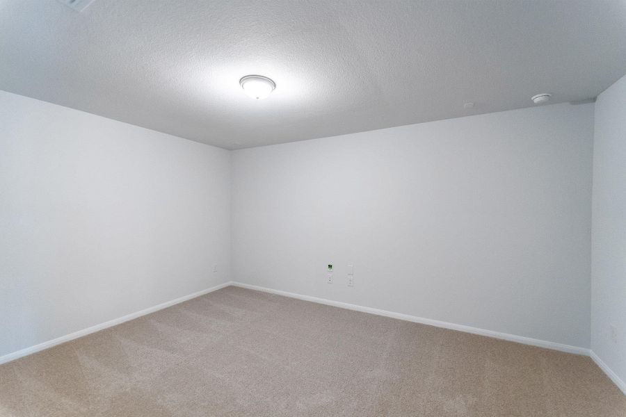Empty room with light colored carpet and a textured ceiling