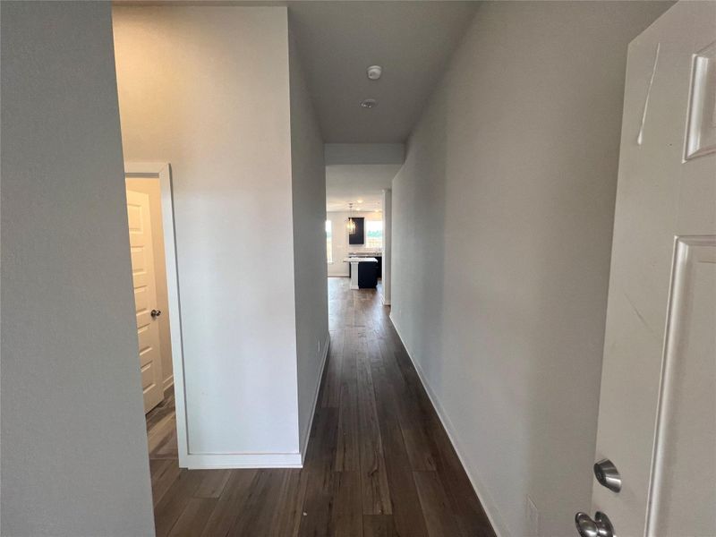 A long entryway with hardwood floors leads to an inviting kitchen space.