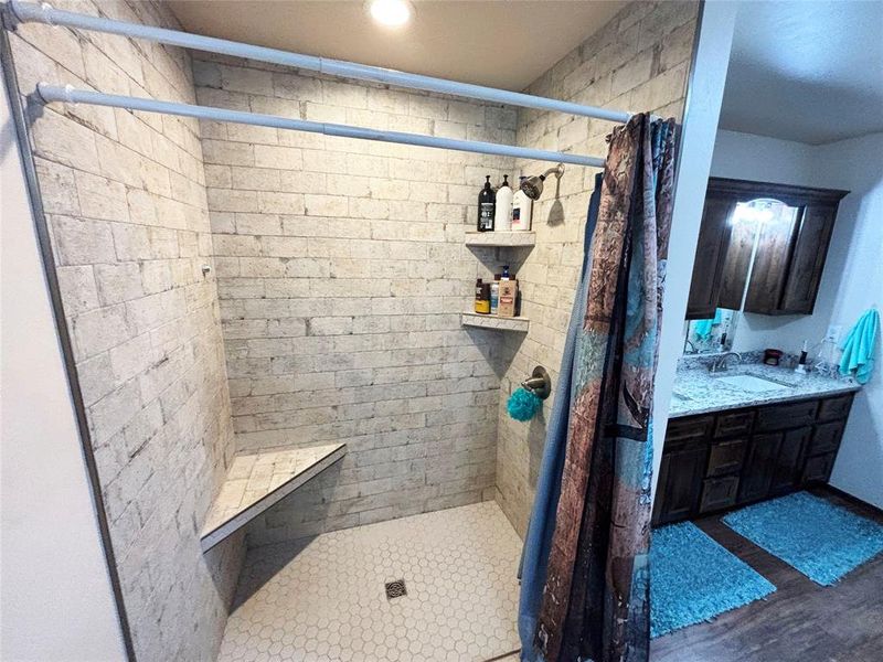 Full bath with a stall shower, vanity, and dark wood-style flooring Full bath with a stall shower, vanity, and dark wood-style flooring