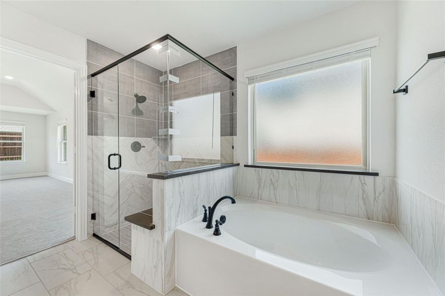 Master bathroom with glass-enclosed walk-in shower, soaking tub, marble tile walls, and black fixtures