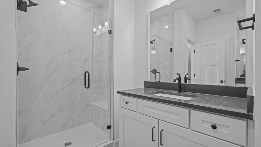Spacious and modern primary bathroom with tiled walk-in shower and first-class separate vanity setup