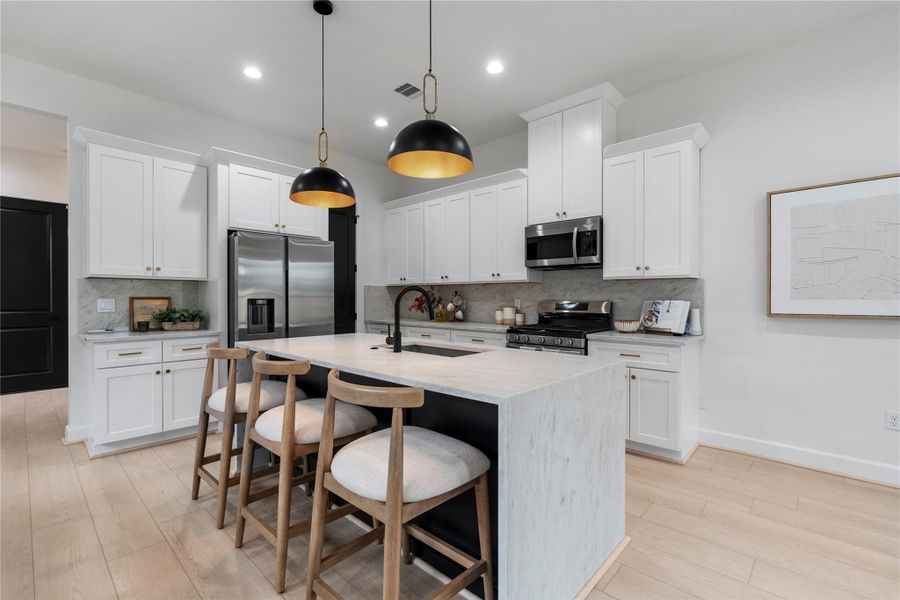 Designer kitchen with waterfall island, bold pendant lighting, and ample storage. Designer kitchen with waterfall island, bold pendant lighting, and ample storage.