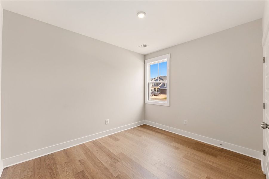 A well-lit bedroom features durable hardwood floor