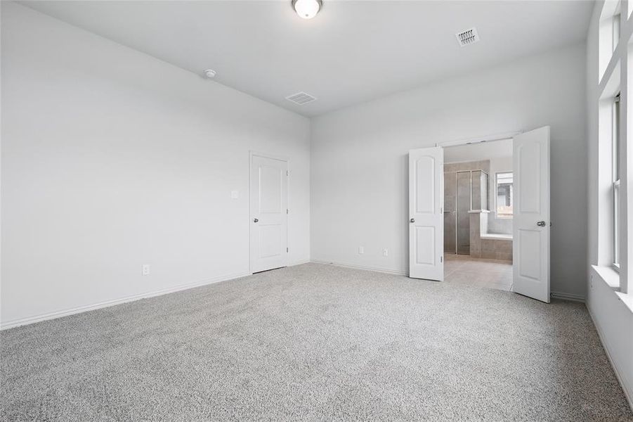 Unfurnished bedroom with light colored carpet and ensuite bath Unfurnished bedroom with light colored carpet and ensuite bath