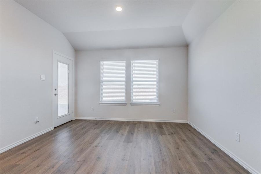 Spare room with light hardwood / wood-style floors and lofted ceiling