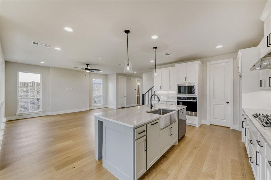Kitchen island featuring a farmhouse sink, pendant lighting, and light-toned countertops