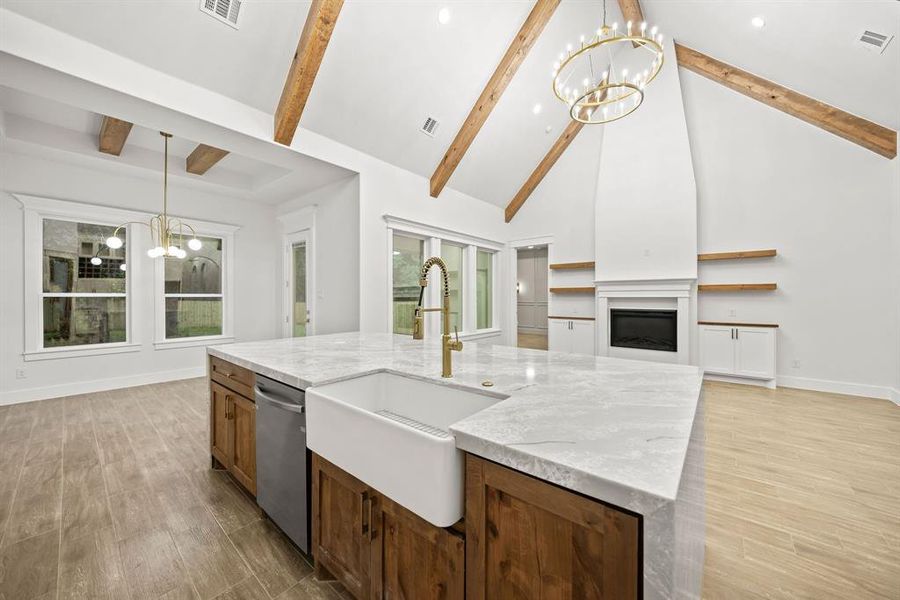Spacious kitchen island featuring a farmhouse sink, stainless steel dishwasher, and stone countertop