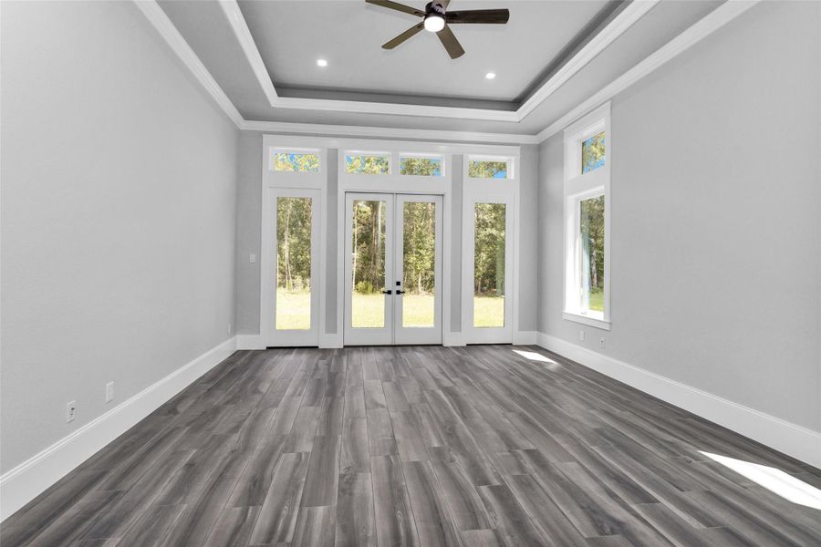 The Primary Suite offers a luxurious haven with frameless double doors opening to the backyard surrounded by a wall of windows & transoms with beautiful millwork and tray ceilings.