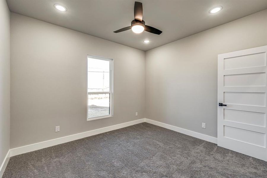 Empty room featuring recessed lighting, dark carpet, baseboards, and a ceiling fan