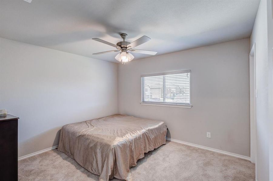 Carpeted bedroom featuring a ceiling fan and baseboards Carpeted bedroom featuring a ceiling fan and baseboards