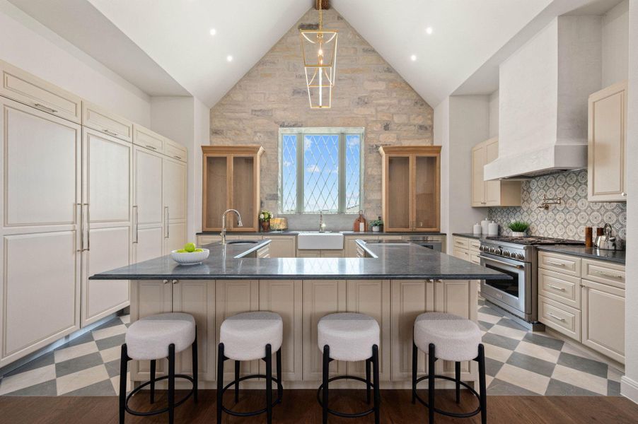 Kitchen with a spacious island, cream cabinets, premium range hood, high end stove, and high vaulted ceiling