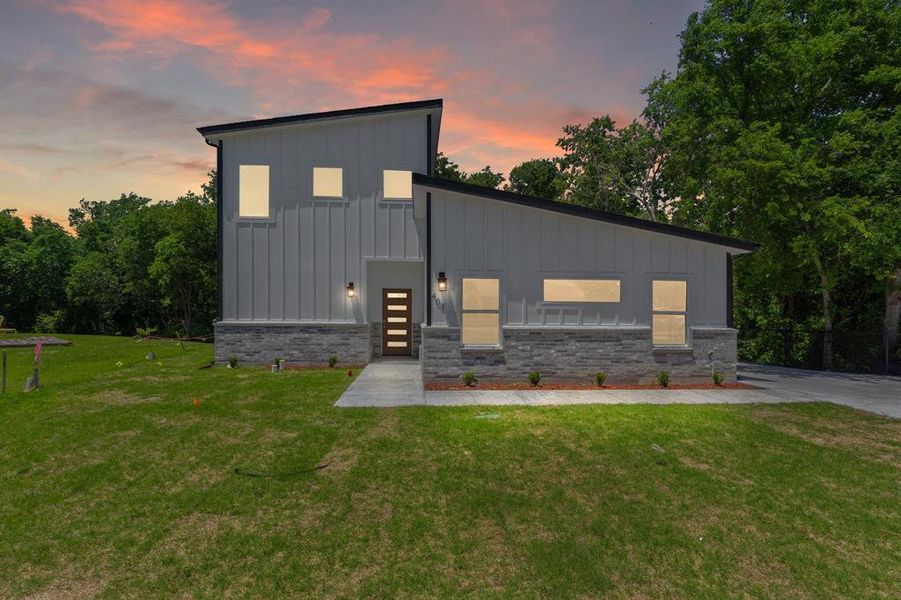 Contemporary house with board and batten siding, a yard, and brick siding Contemporary house with board and batten siding, a yard, and brick siding