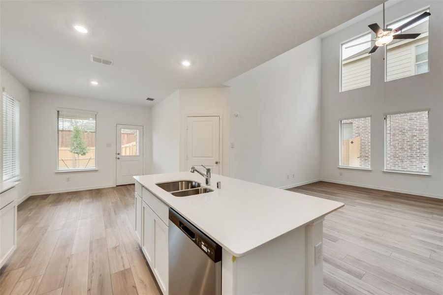 Kitchen with dishwasher, a kitchen island with sink, sink, white cabinetry, and ceiling fan