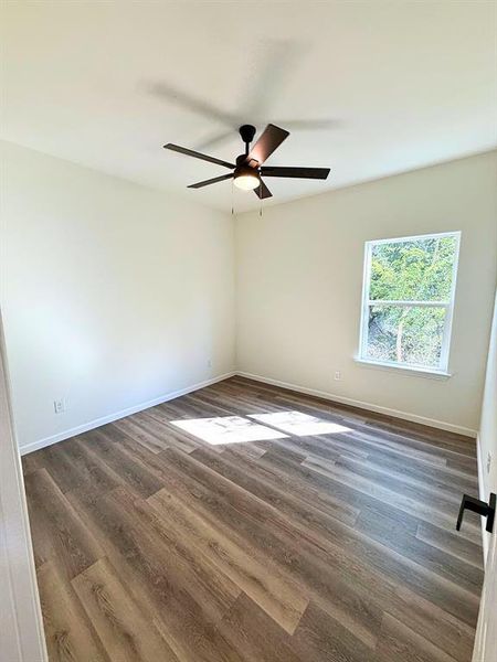 Unfurnished room with dark wood-type flooring and a ceiling fan