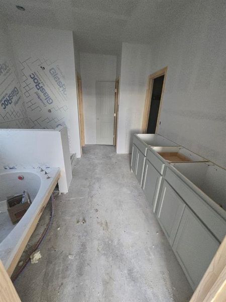 Full bath with vanity, concrete flooring, and a garden tub