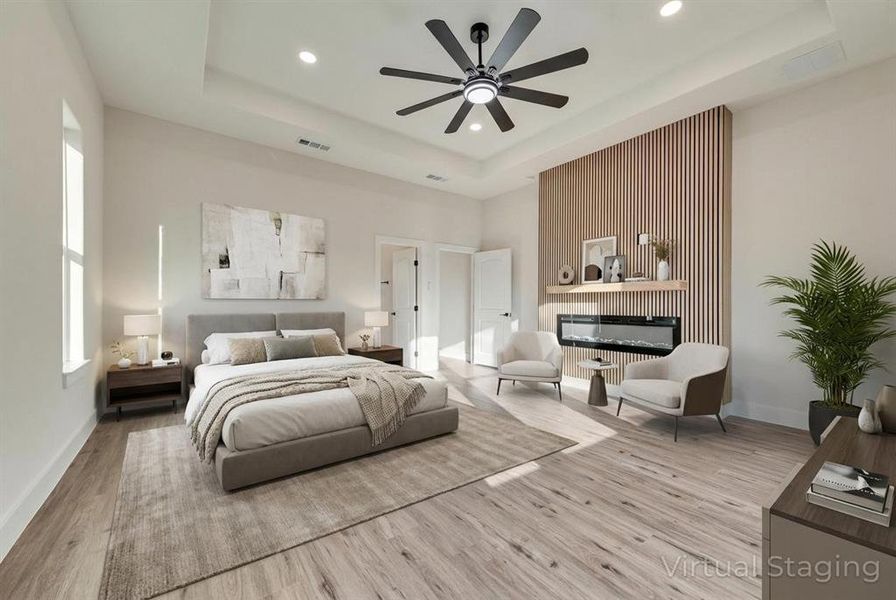 Virtually Staged Bedroom featuring a glass covered fireplace, a tray ceiling, light wood finished floors, ceiling fan, and recessed lighting