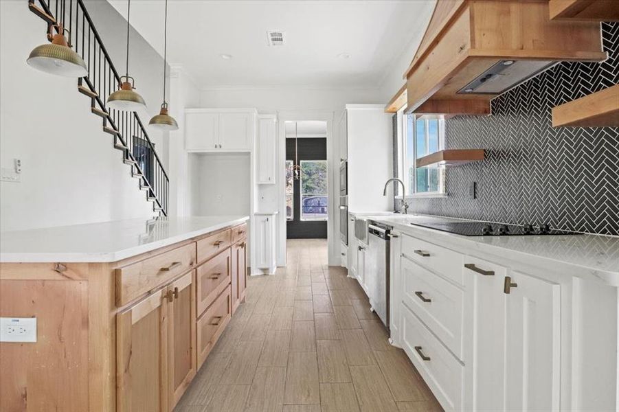Kitchen with decorative backsplash, open shelves, white cabinets, and light stone countertops