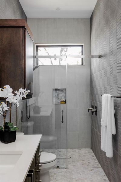 The bathroom features refined stone surfaces, custom cabinetry, and curated tile selections, creating a clean, modern aesthetic and a convenient over-sized walk-in shower. The bathroom features refined stone surfaces, custom cabinetry, and curated tile selections, creating a clean, modern aesthetic and a convenient over-sized walk-in shower.