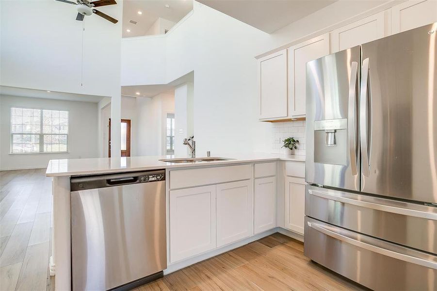 Kitchen featuring kitchen peninsula, white cabinetry, sink, and stainless steel appliances