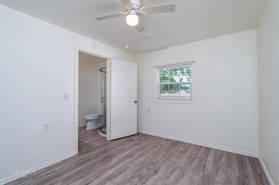 Unfurnished bedroom featuring connected bathroom, hardwood / wood-style floors, and ceiling fan