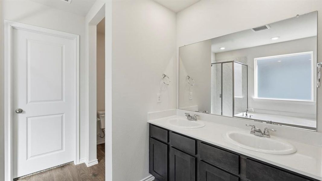 Full bathroom featuring a garden tub, double vanity, dark wood finished floors, and a stall shower Full bathroom featuring a garden tub, double vanity, dark wood finished floors, and a stall shower