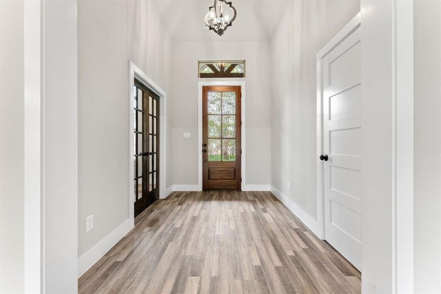 Foyer with light wood-type flooring and a notable chandelier