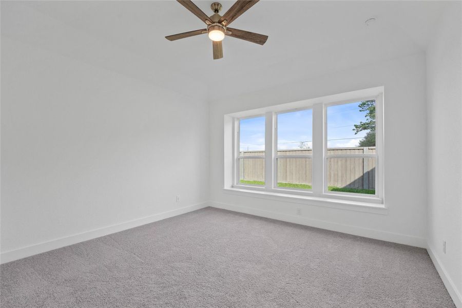 Relax and unwind after a long day in this impressive primary suite! This generously sized room offers plush carpeting, warm-toned paint, high ceilings with a ceiling fan, and large windows for added comfort and tranquility.
