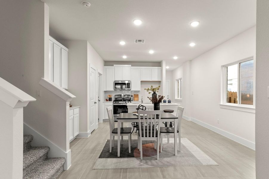 Bright open-concept kitchen and dining area features abundant cabinetry and seamless flooring.