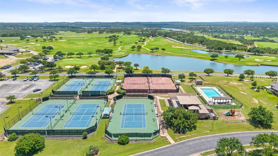 Recreational amenities featuring multiple tennis courts, a swimming pool, and a playground, all set against a backdrop of a golf course and a body of water