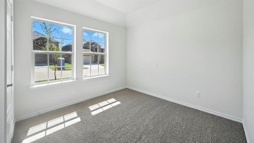 Bright room featuring two large sash windows with multiple panes, neutral-toned carpeting, white baseboards, and a white interior door Bright room featuring two large sash windows with multiple panes, neutral-toned carpeting, white baseboards, and a white interior door