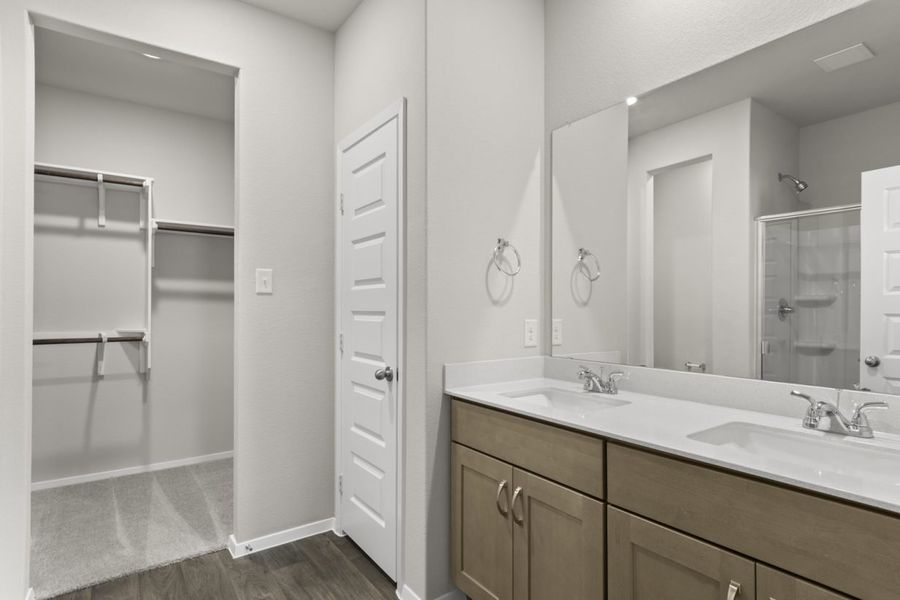 Image of primary bathroom with light brown cabinets and a large mirror with vanity and a connected closet Image of primary bathroom with light brown cabinets and a large mirror with vanity and a connected closet