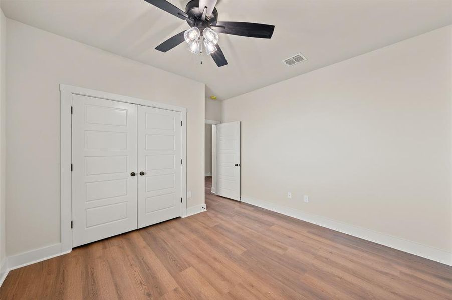 Unfurnished bedroom featuring light wood-type flooring, ceiling fan, and a closet
