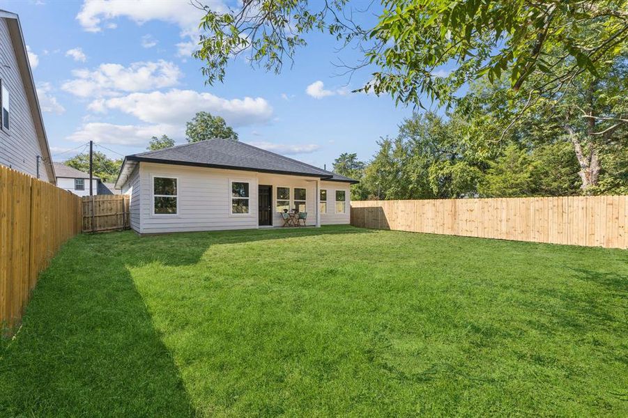 Rear view of property with a fenced backyard, a patio area, and a shingled roof