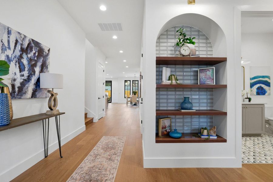Corridor with light wood finished floors, recessed lighting, and built in shelves