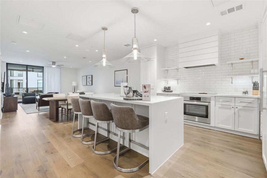 Kitchen featuring white cabinets, pendant lighting, open shelves, open floor plan, and tasteful backsplash