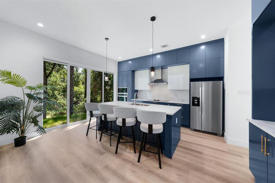 Kitchen with blue cabinets, stainless steel appliances, a center island with sink, a kitchen bar, and modern cabinets Kitchen with blue cabinets, stainless steel appliances, a center island with sink, a kitchen bar, and modern cabinets