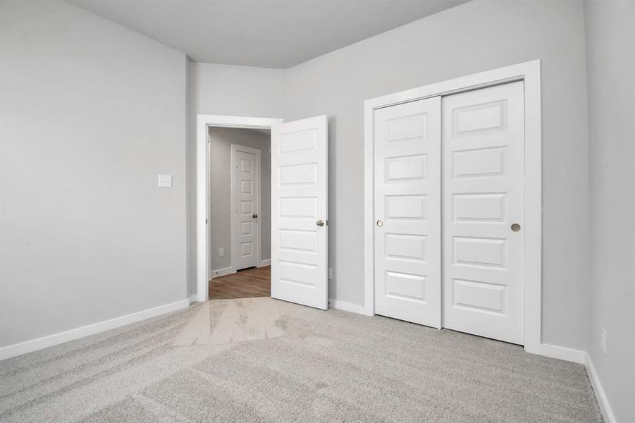 Generously sized secondary bedrooms featuring spacious closets, soft and inviting carpeting underfoot, large windows allowing plenty of natural light. Sample photo of completed home. As-built color and selections may vary.