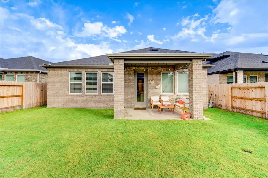Impressive rear elevation of this beautiful home features a spacious covered veranda, thoughtfully designed as a comfortable sitting area that maximizes outdoor living. This inviting space provides the perfect setting for relaxation, as well as for hosting backyard barbecues and gatherings with family and friends, all while enjoying the surrounding outdoor ambiance.