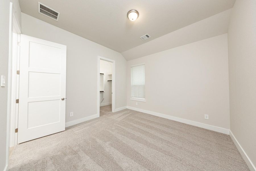This inviting secondary bedroom combines comfort and modern elegance, featuring sloped ceiling, plush carpeting, a neutral color palette, abundant natural light streaming through a large window, and a walk-in closet. This inviting secondary bedroom combines comfort and modern elegance, featuring sloped ceiling, plush carpeting, a neutral color palette, abundant natural light streaming through a large window, and a walk-in closet.
