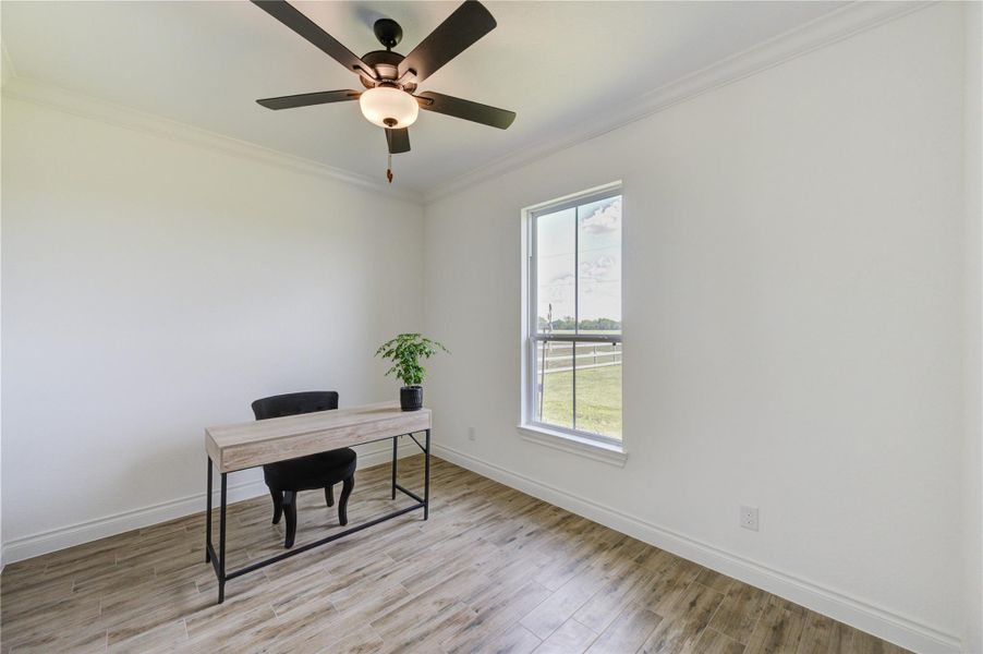 Bright home office or flex space with wood-look tile floors and peaceful outdoor views.